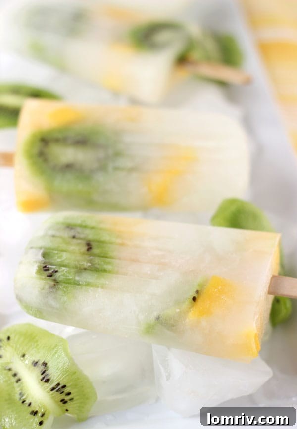 Close-up of a refreshing mango kiwi lemonade popsicle, showing distinct layers of kiwi and mango with a lemonade base, perfect for summer hydration.