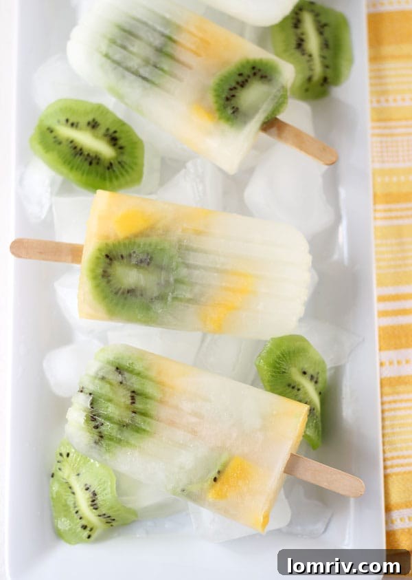 Multiple mango kiwi lemonade popsicles laid out, highlighting their refreshing layers and vibrant colors, ready for a hot day.
