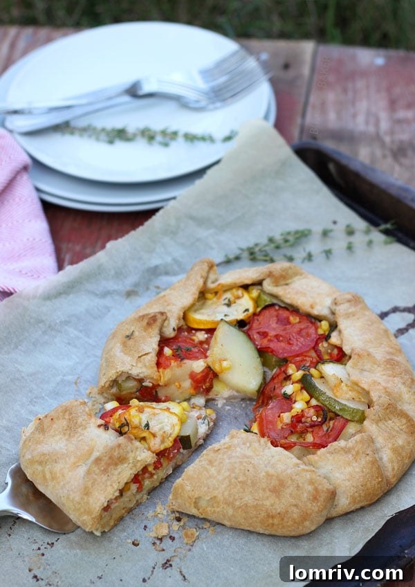 A single, perfectly cut slice of homemade summer vegetable galette, revealing its layers of crust, cheese, and vegetables