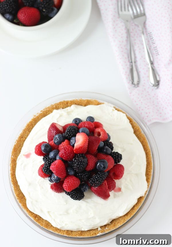 A slice of white chocolate cheesecake pie, showcasing its layers of crust, filling, and berry topping