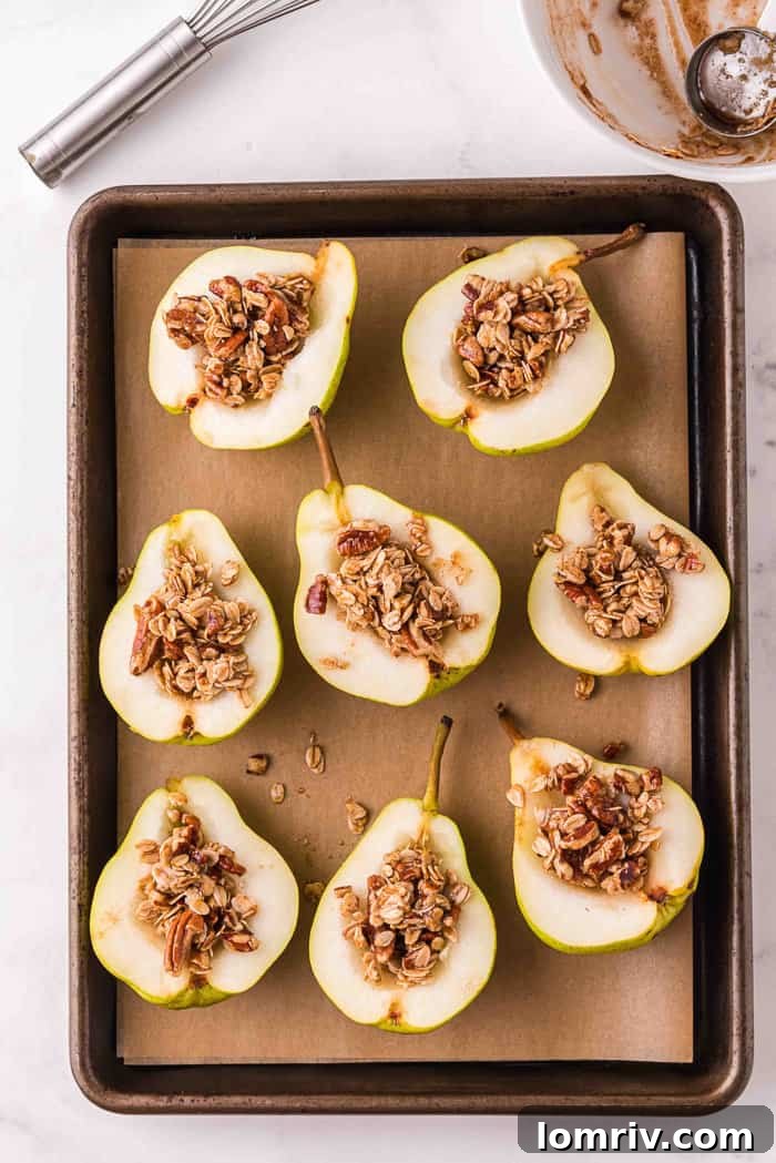 Baked pears on a cookie sheet, with oat crumble filling the centers