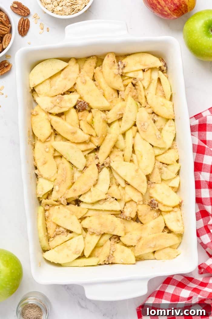 A baking dish filled with the seasoned apple mixture, ready for the streusel topping.