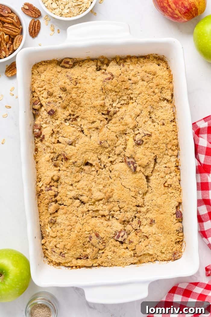 A freshly baked apple cardamom crisp, bubbling and golden brown with a perfectly toasted streusel topping, still in its white baking dish.