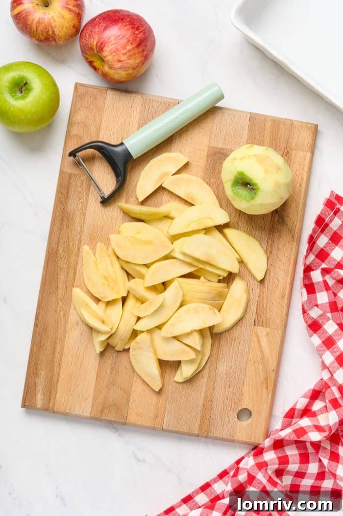 Peeled and uniformly sliced apples arranged neatly on a wooden cutting board, ready for the crisp filling.