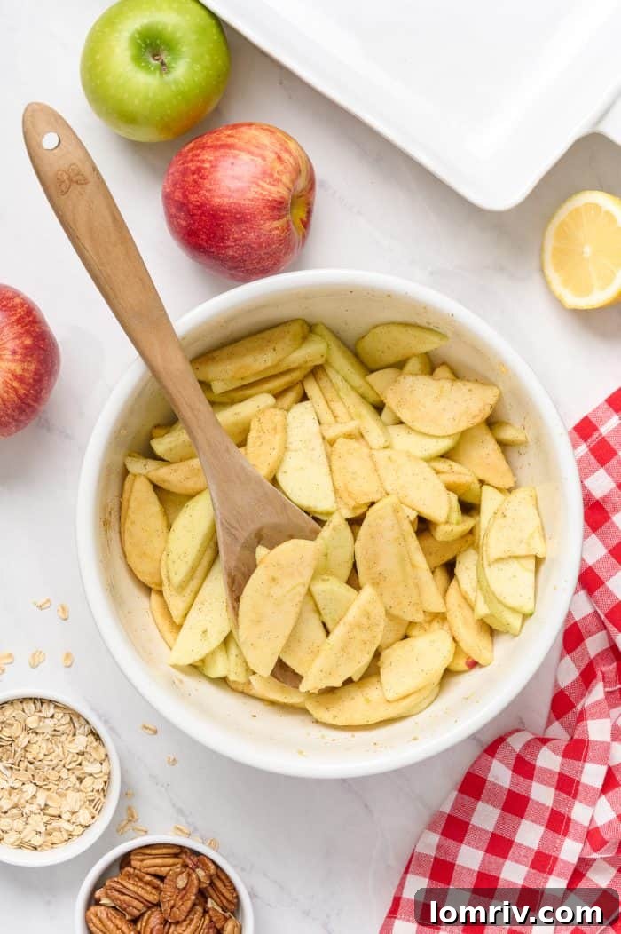 A closer view of spiced apple slices in a white bowl, glistening with lemon juice and brown sugar.