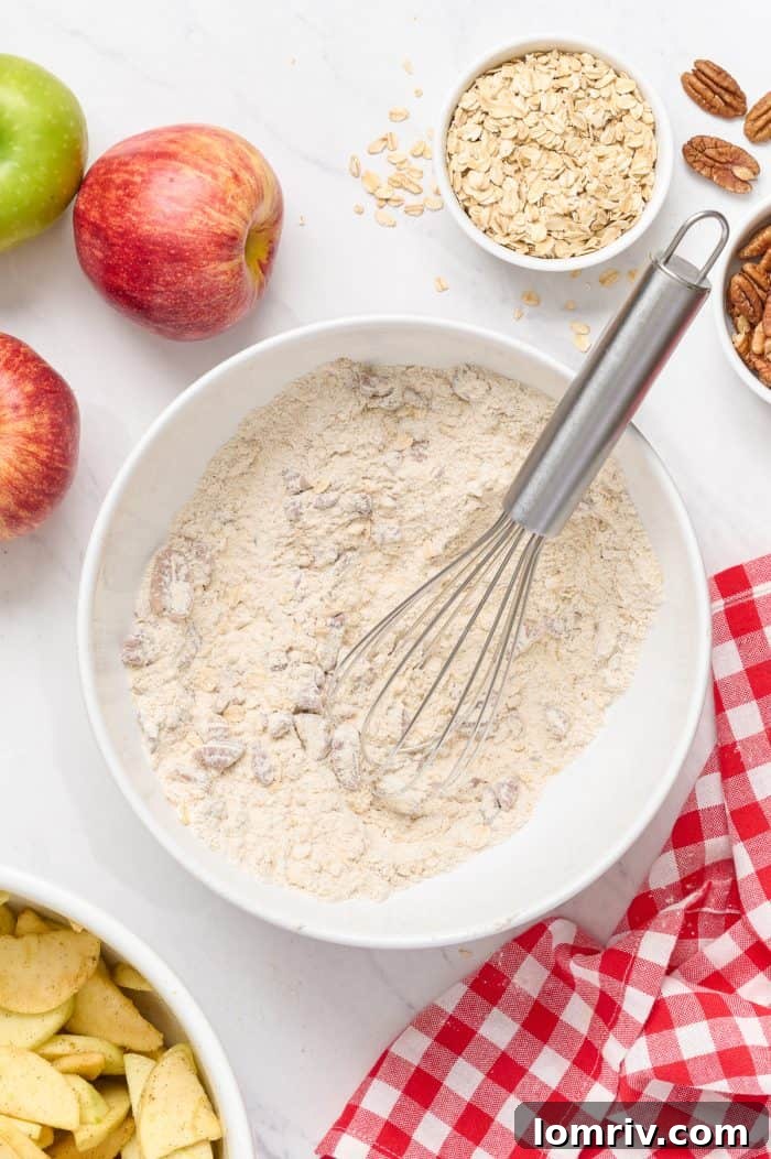 A white bowl filled with the dry ingredients for the streusel topping: flour, brown sugar, cinnamon, pecans, and oats.
