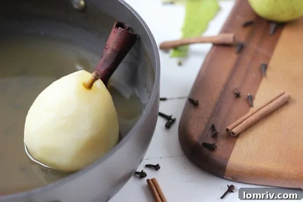 Close-up of poached pears simmering in spiced cider and white wine