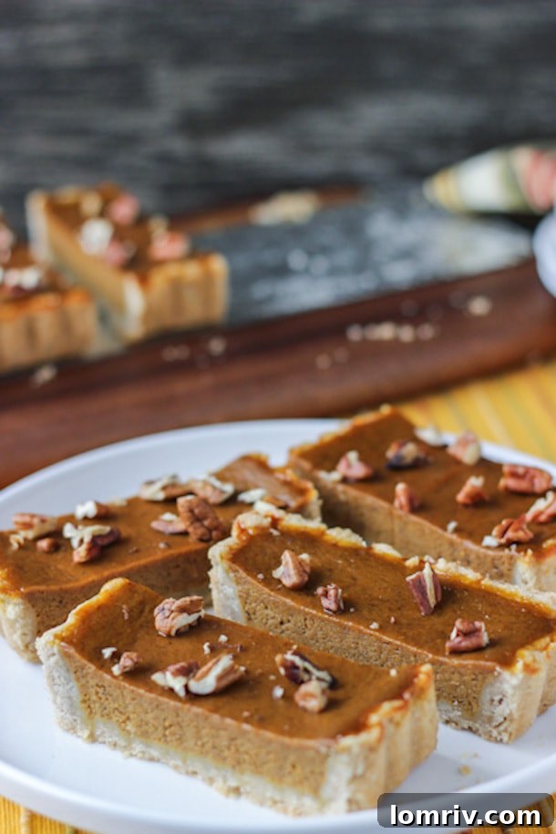 An elegantly crafted Pumpkin Maple Tart, featuring a golden, spiced pecan crust and a creamy filling, presenting a refined choice for Thanksgiving dessert.