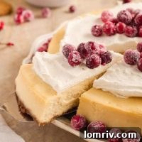 Creamy eggnog cheesecake with a spiced gingersnap crust, topped with whipped cream and sugared cranberries.