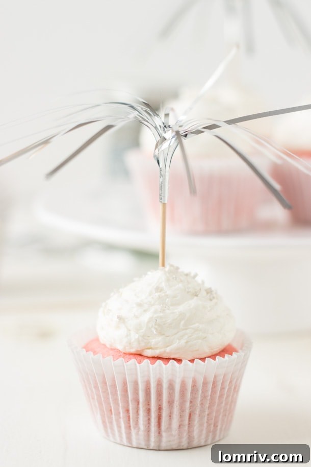 Pretty pink champagne cupcakes filled with a creamy pastry creme and topped with a sweet champagne frosting, perfect for a festive New Year's Eve dessert.