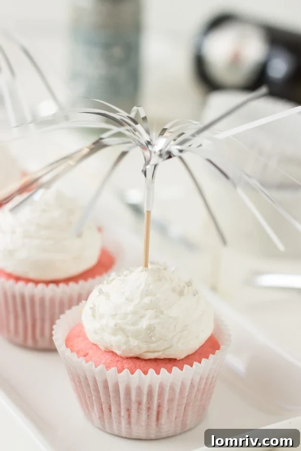 Close-up of a pink champagne cupcake, showcasing the delicate pink hue and creamy frosting, a perfect bubbly dessert.