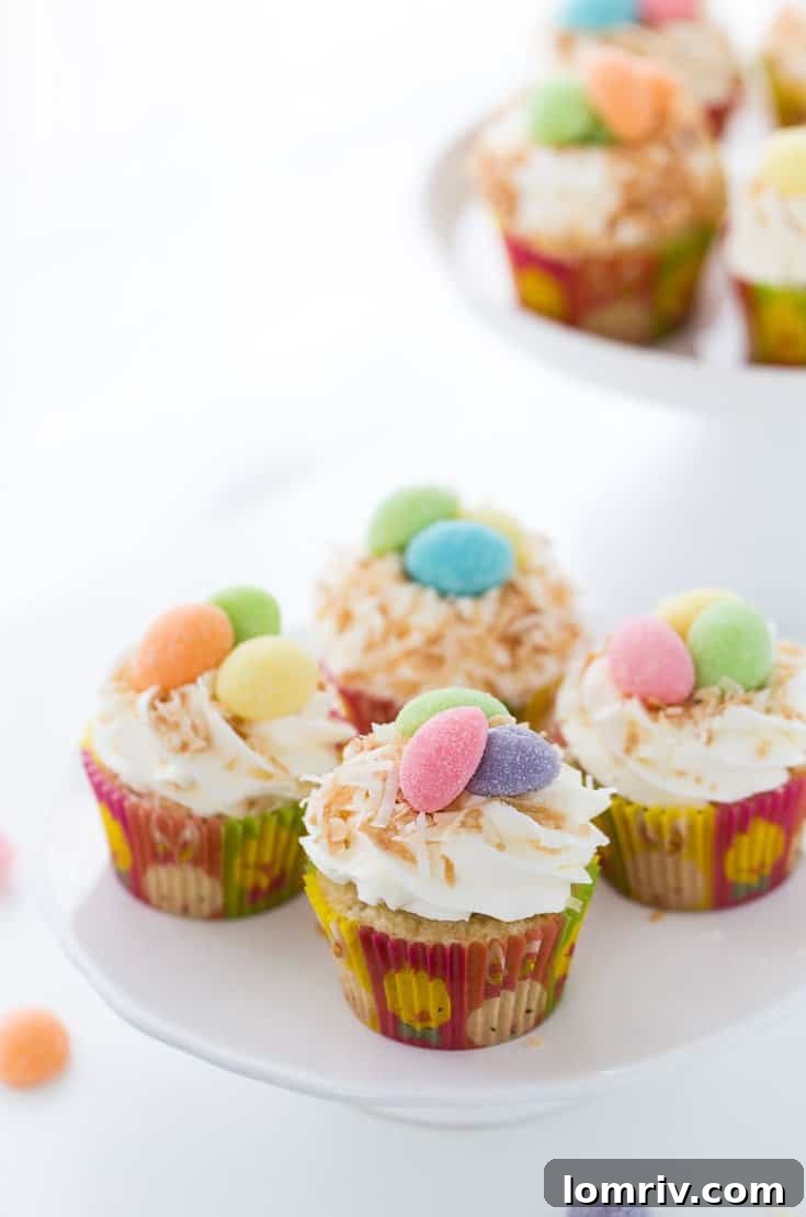 Beautifully decorated coconut cupcakes, featuring a sweet whipped coconut frosting and festive Easter candy toppers.