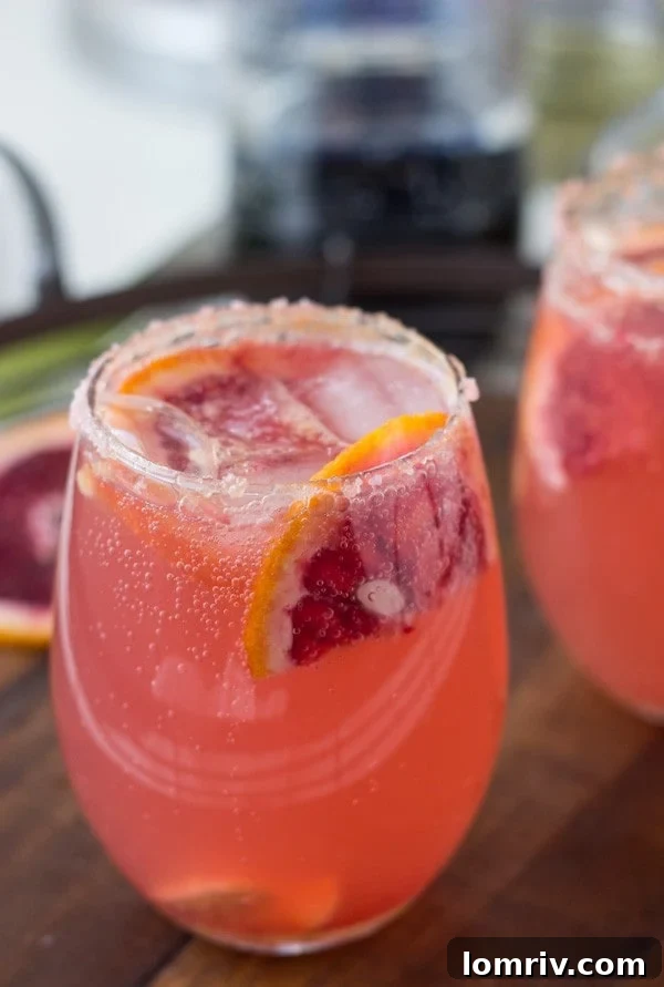 Close-up of sparkling grapefruit cocktails ready for a party, featuring a grapefruit rosemary sparkler and a grapefruit ginger-orange cocktail with ice and garnishes.