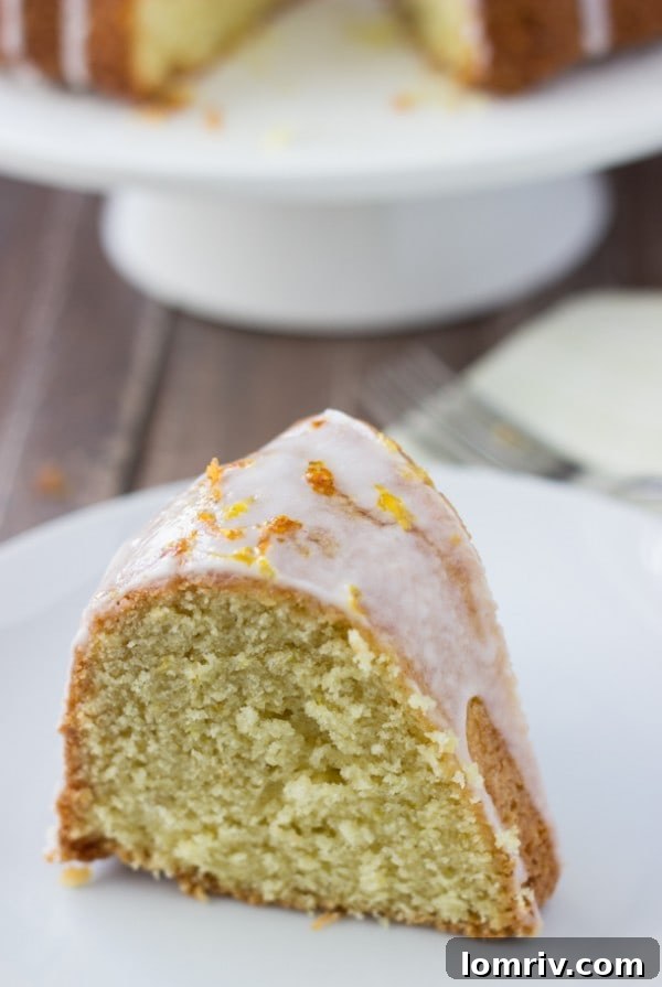 Grapefruit-Orange-Pound Cake: A beautifully plated slice of pound cake with a generous drizzle of citrus glaze and a garnish of fresh grapefruit peel.