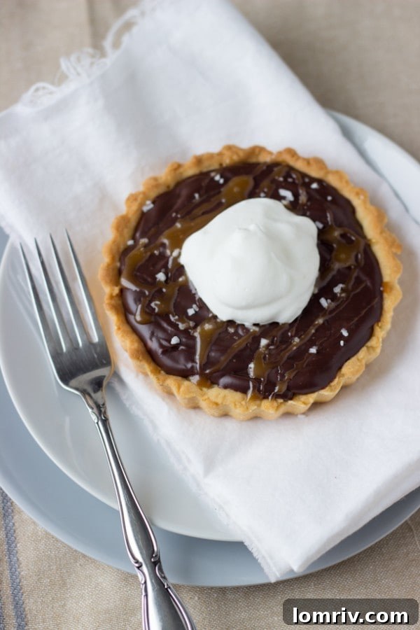 Several mini Caramelized Dark Chocolate Tarts arranged on a serving plate.
