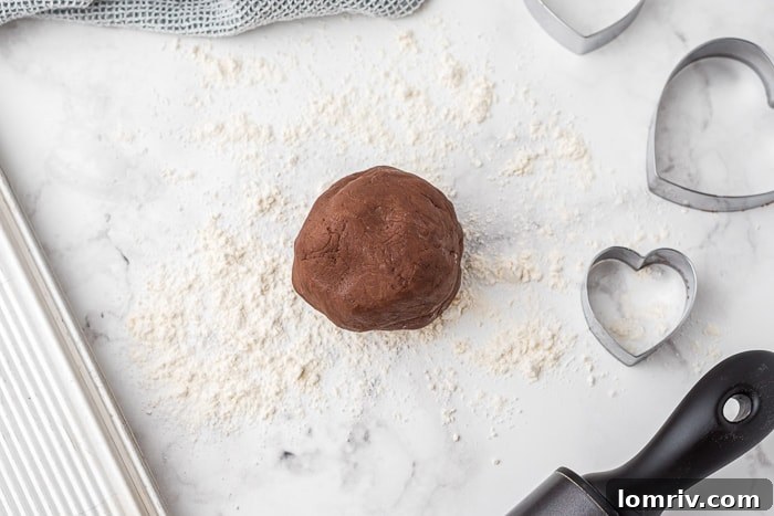 Rolling out chocolate cookie dough on a floured surface