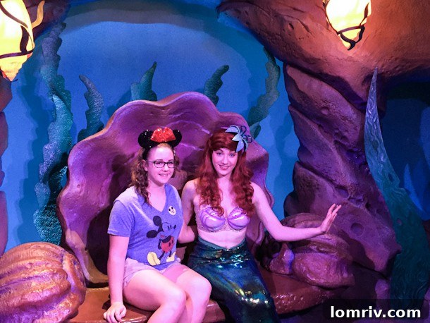 The author proudly stands beside a vibrant display featuring Ariel, her favorite Disney princess, at Magic Kingdom.
