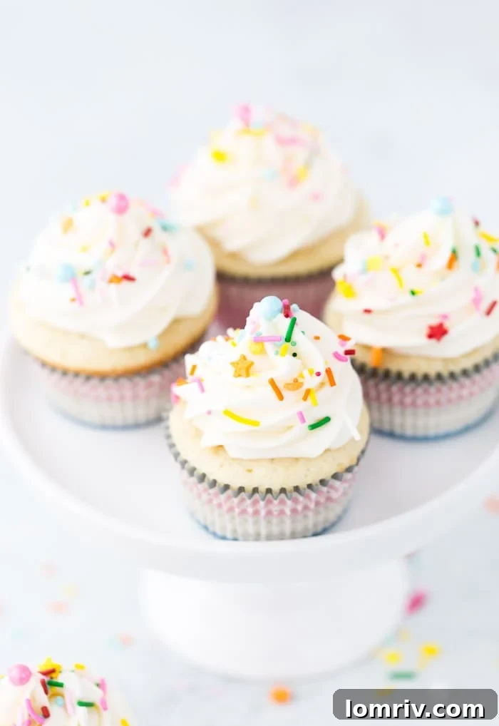 A beautifully arranged tray of vanilla cupcakes, topped with creamy cream cheese frosting and a sprinkle of festive decoration, ready to be enjoyed.