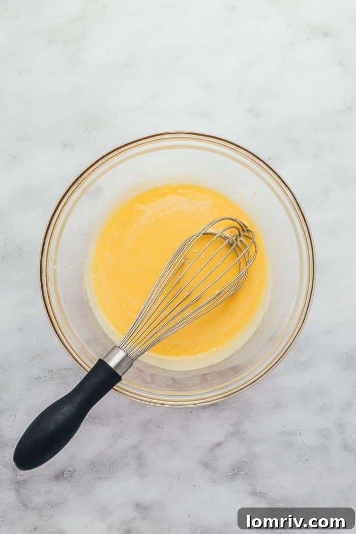 A glass bowl containing the Key Lime Pie filling ingredients, being whisked to achieve a smooth consistency.