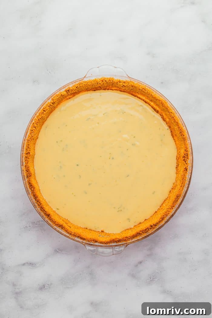 A graham cracker crust brimming with the creamy, vibrant Key Lime filling, ready for baking.