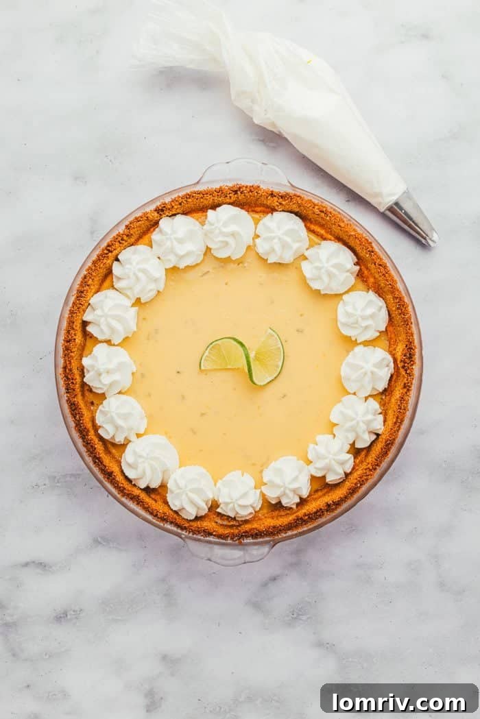 A Key Lime Pie beautifully garnished with generous swirls of whipped cream, inviting a taste.