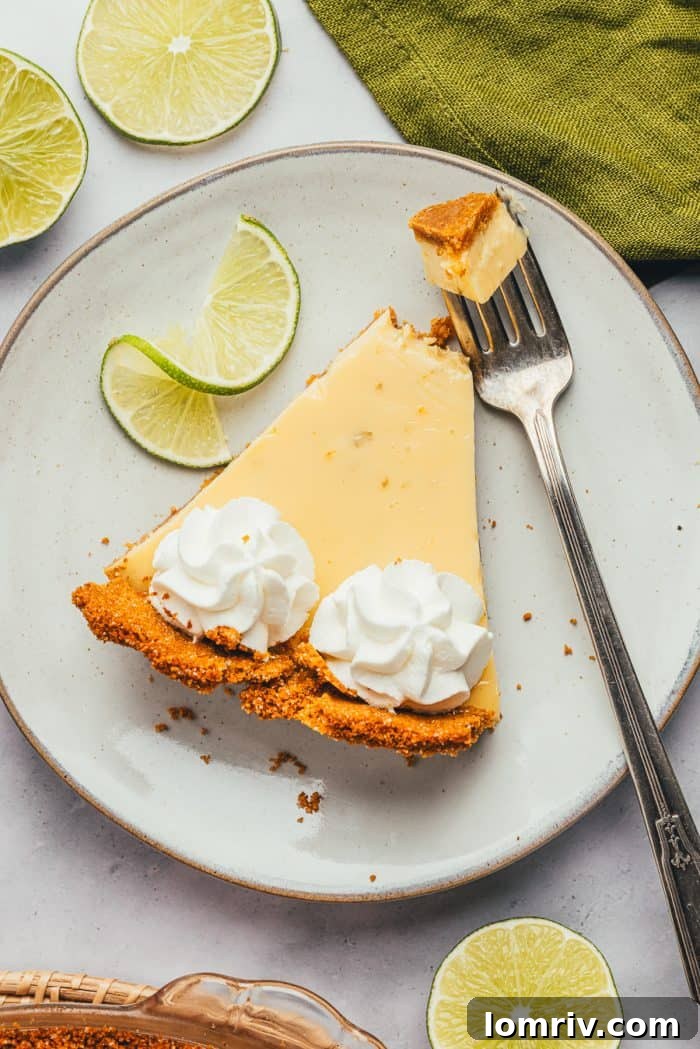 A Fork is piercing into a luscious slice of Key Lime Pie, showcasing its soft, inviting texture.