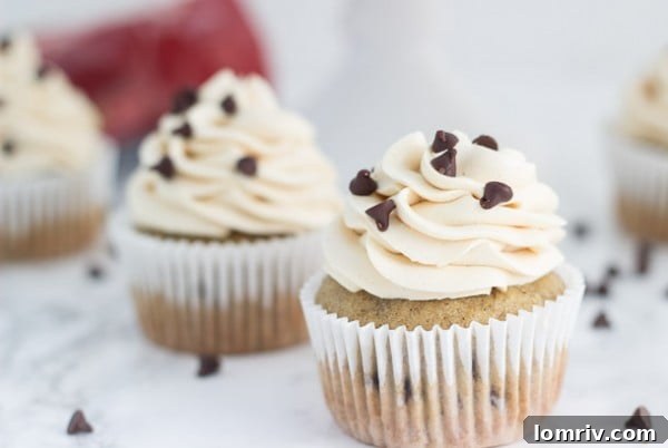Two frosted Chocolate Chip Banana Cupcakes on a white surface