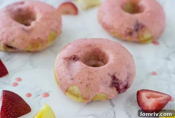 A plate of freshly baked strawberry lemon donuts, showcasing their beautiful shape and enticing pink glaze.