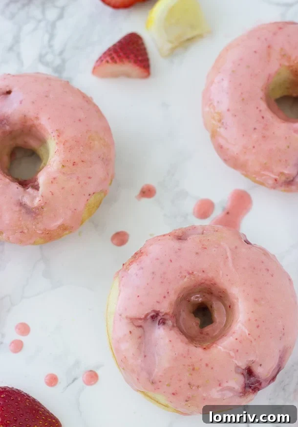 Close-up of a soft, moist strawberry lemon baked donut, highlighting its delicate texture and the generous strawberry glaze.