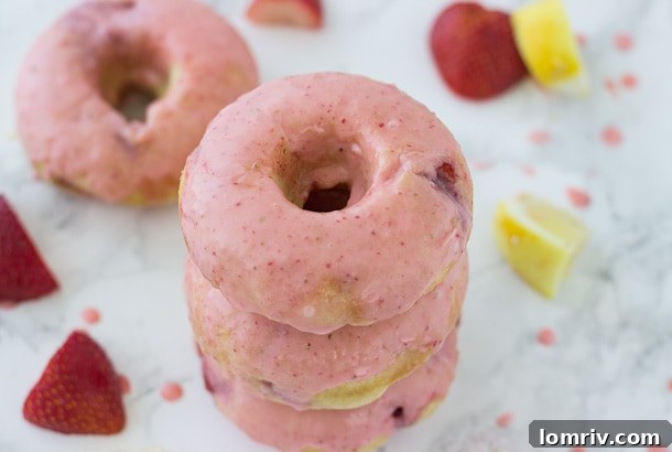 A stack of perfectly glazed strawberry lemon baked donuts on a cooling rack, ready to be enjoyed.
