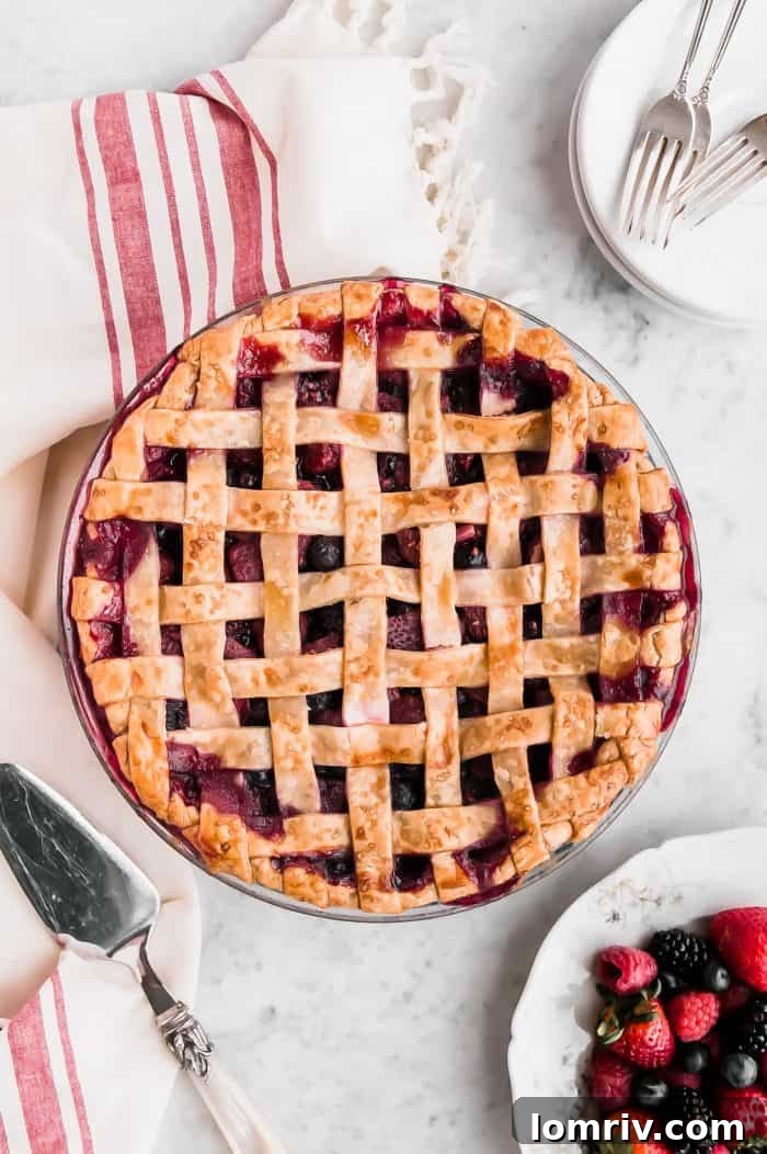 A beautifully baked Mixed Berry Pie with a golden lattice crust, showcasing juicy strawberries, blackberries, and blueberries inside.