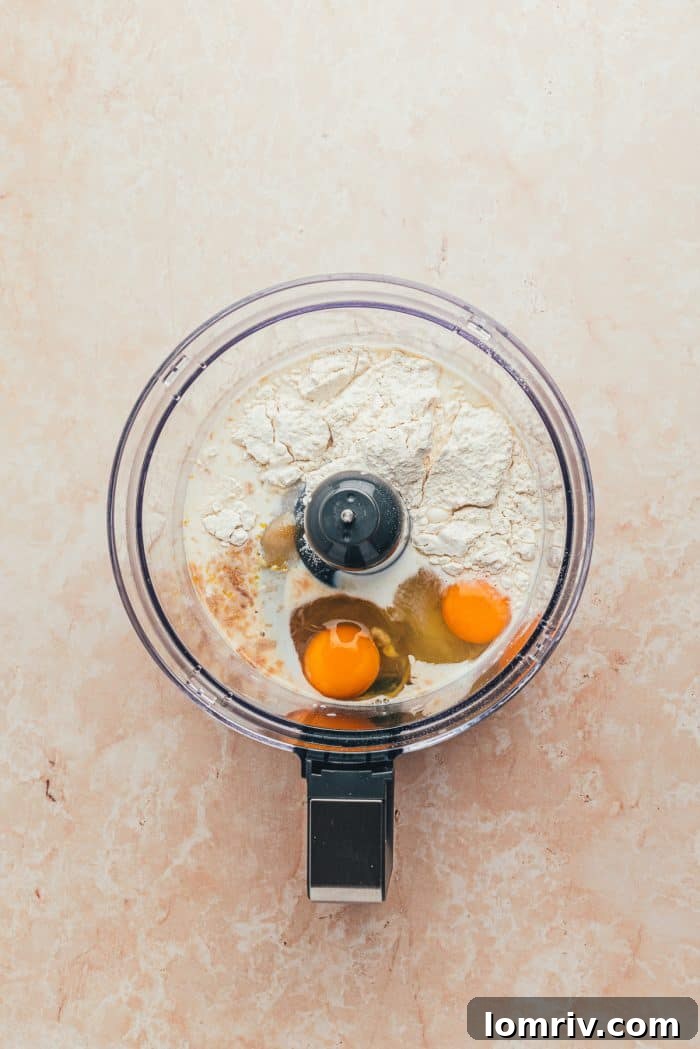 The ingredients to make a blueberry Dutch baby pancake in a food processor.