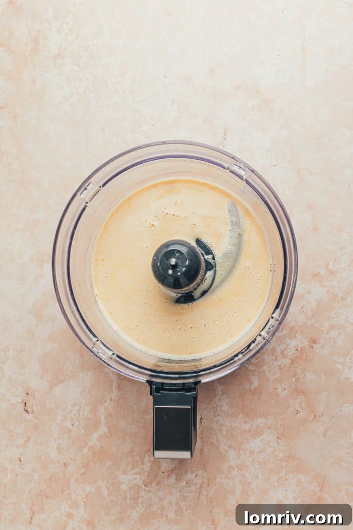The blended ingredients to make a blueberry Dutch baby pancake in a food processor.