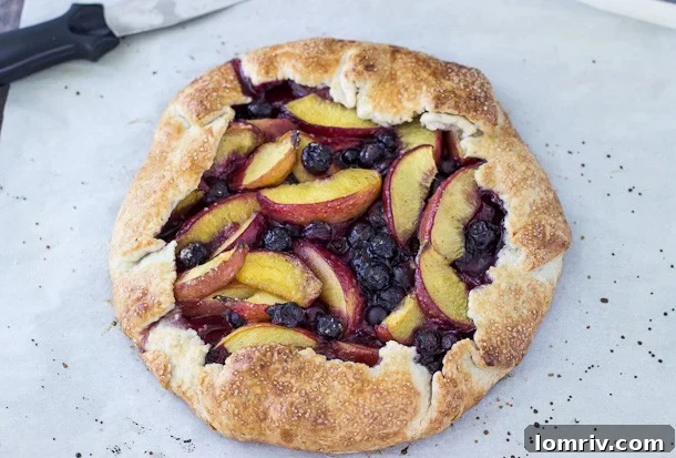 A delectable slice of peach blueberry galette, served warm, revealing its tender crust and luscious fruit filling.