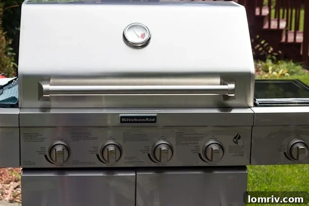 Happy husband with new KitchenAid 4-burner gas grill, ready for summer BBQs
