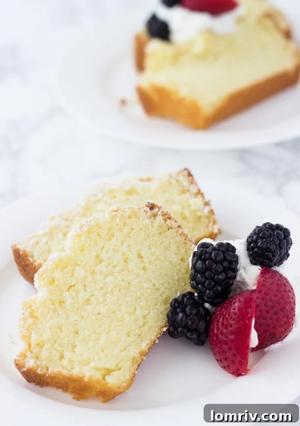A beautifully decorated slice of Meyer Lemon Pound Cake with fresh berries and whipped cream.