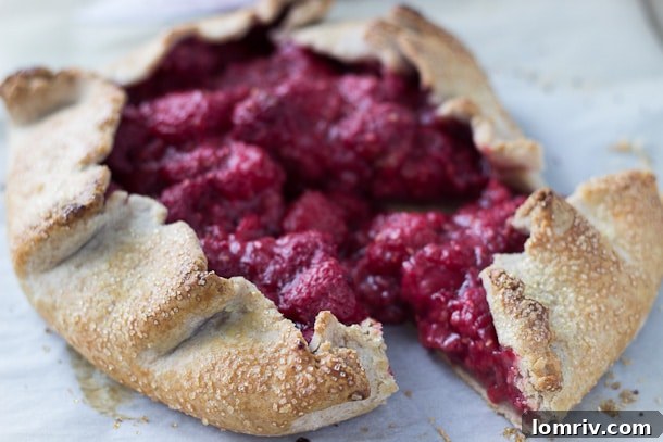 Close-up of a slice of Raspberry Vanilla Bean Galette, showcasing the vibrant raspberry filling and golden crust.