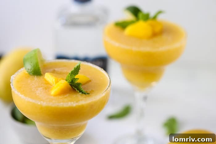 Close-up of a glass of Frozen Mango Margarita, garnished with fresh lime