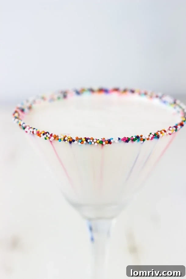 Another beautiful shot of the Birthday Cake Martini, emphasizing the elegant presentation with the sprinkle-rimmed glass. The focus is on the drink's appealing color and texture, highlighted by festive lighting, perfect for a celebratory toast.