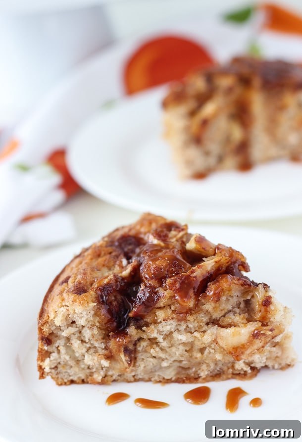 Close-up of a slice of Caramel Apple Crumb Cake, revealing its moist texture, tender apple pieces, and decadent swirls of cinnamon and caramel throughout the cake.
