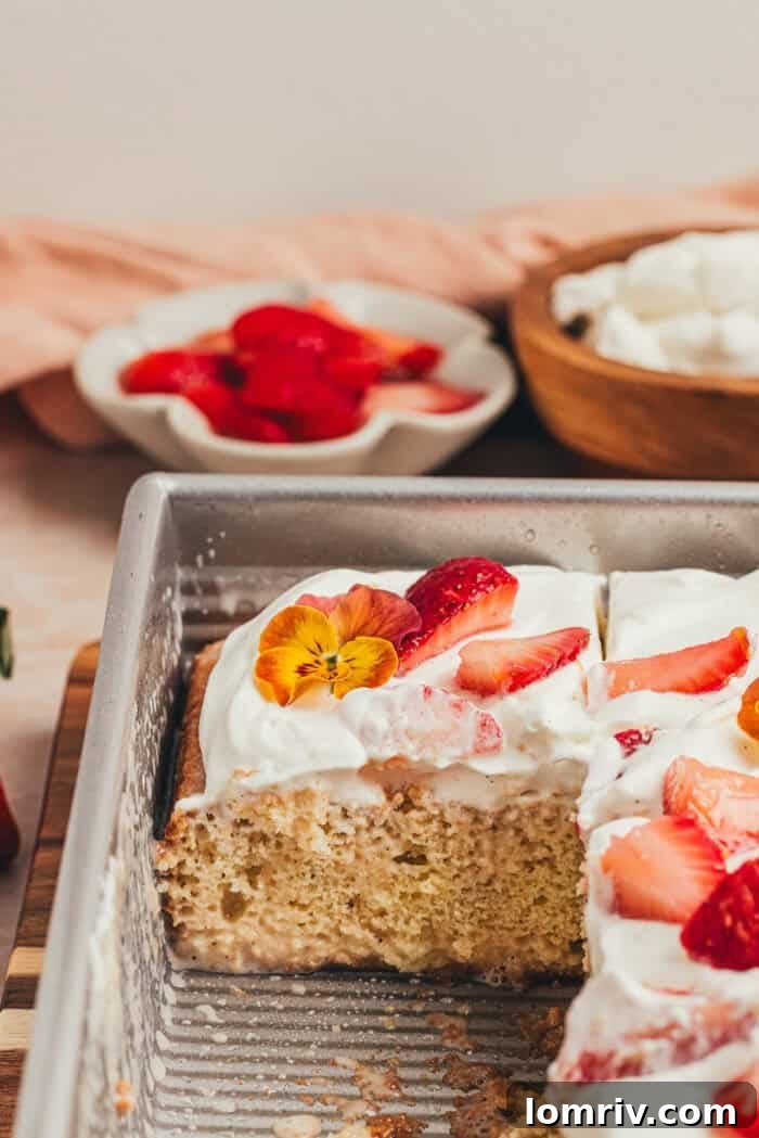 A cake pan filled with perfectly sliced strawberry tres leches cake, ready to serve.
