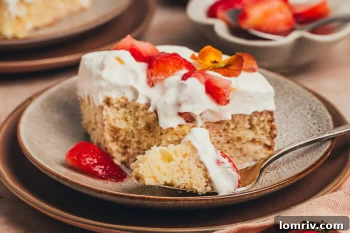 A beautifully plated slice of strawberry tres leches cake, with a fork digging in.