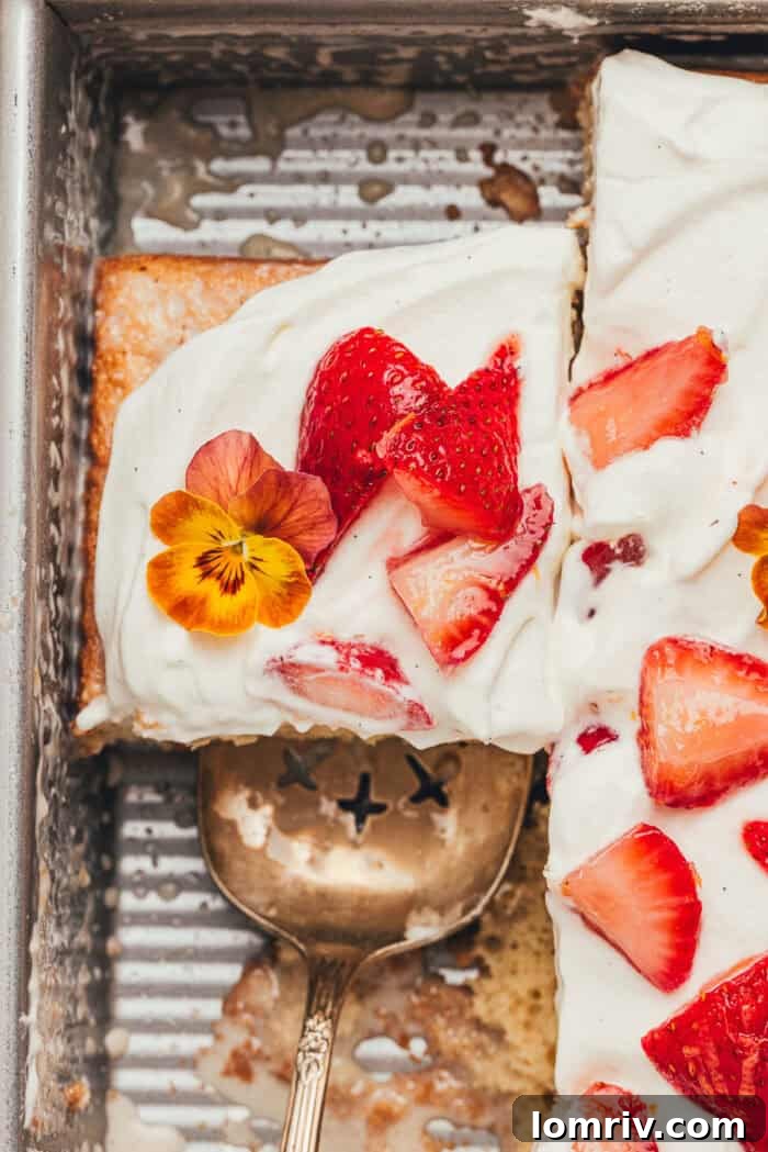 Close-up view of sliced strawberry tres leches cake in a baking pan, showing the moist interior.