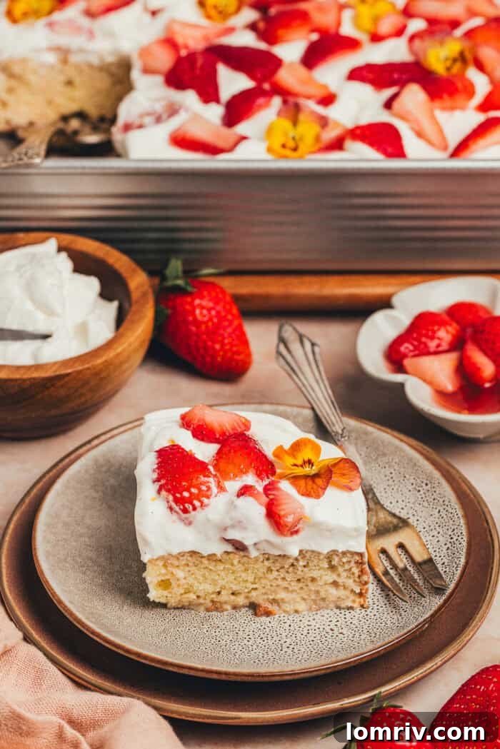 A delectable slice of strawberry tres leches cake on a plate with a fork poised to take a bite.