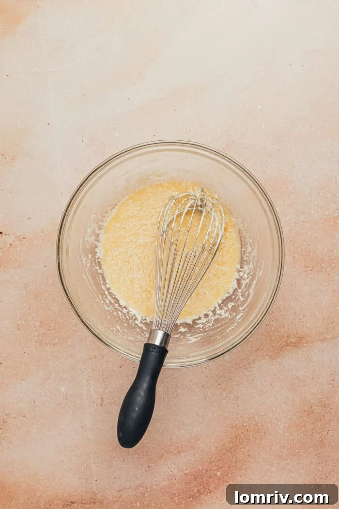 Wet ingredients for the cupcakes being whisked together in a separate glass bowl.