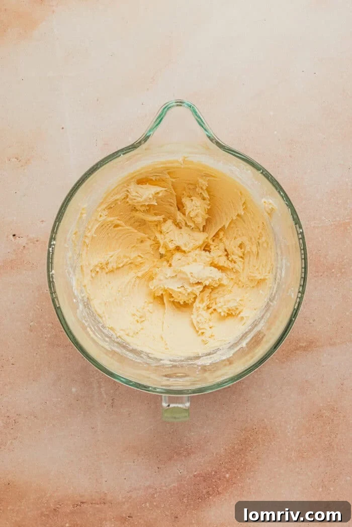 Softened unsalted butter being creamed in the bowl of a stand mixer.