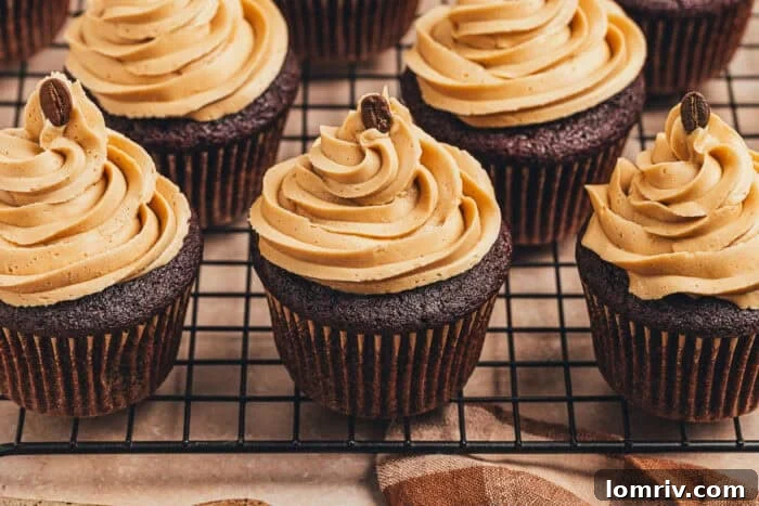 A grid of nine chocolate cupcakes with swirls of espresso frosting on a wire cooling rack.