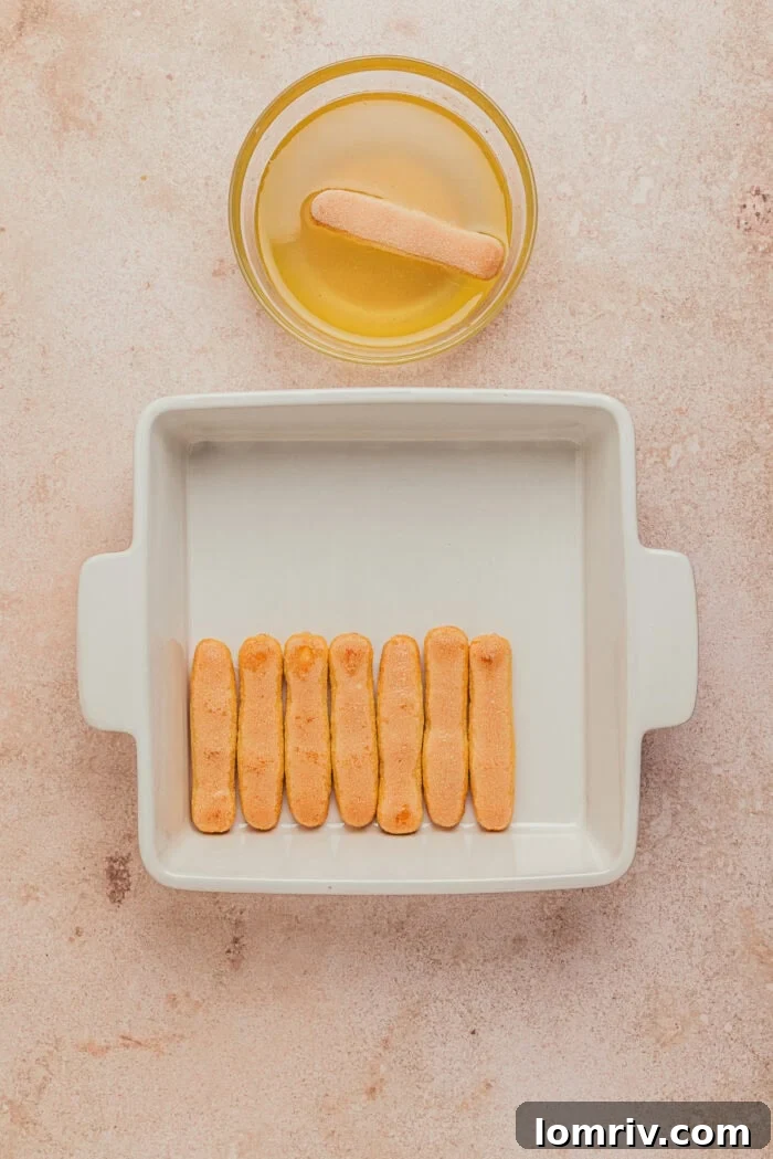 A square dish with the lady fingers dipped into a syrup and placed on the bottom of the dish.