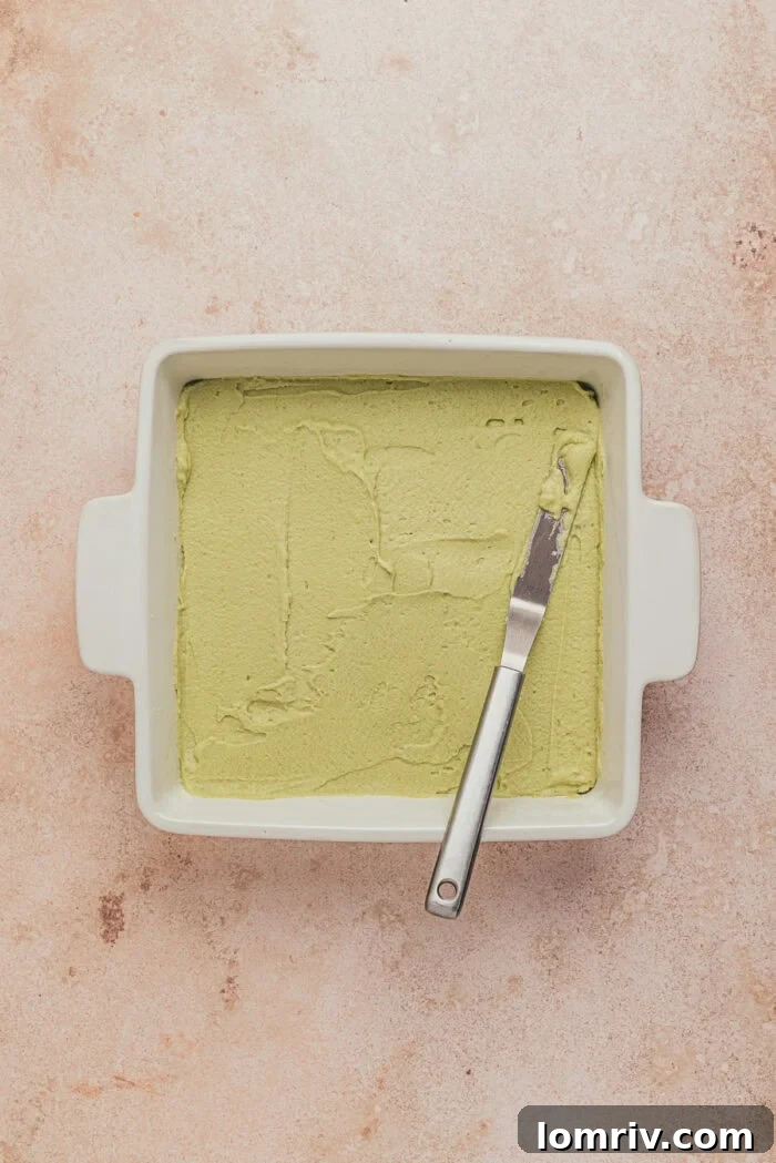 A square dish with the first layer of the lemon pistachio tiramisu.