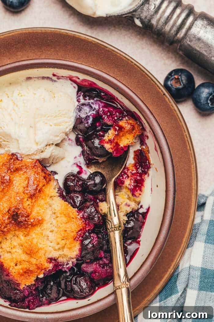 Honey-Sweetened Blueberry Cobbler Recipe with Fresh Berries 6 A bowl with a serving of blueberry cobbler and a spoon.